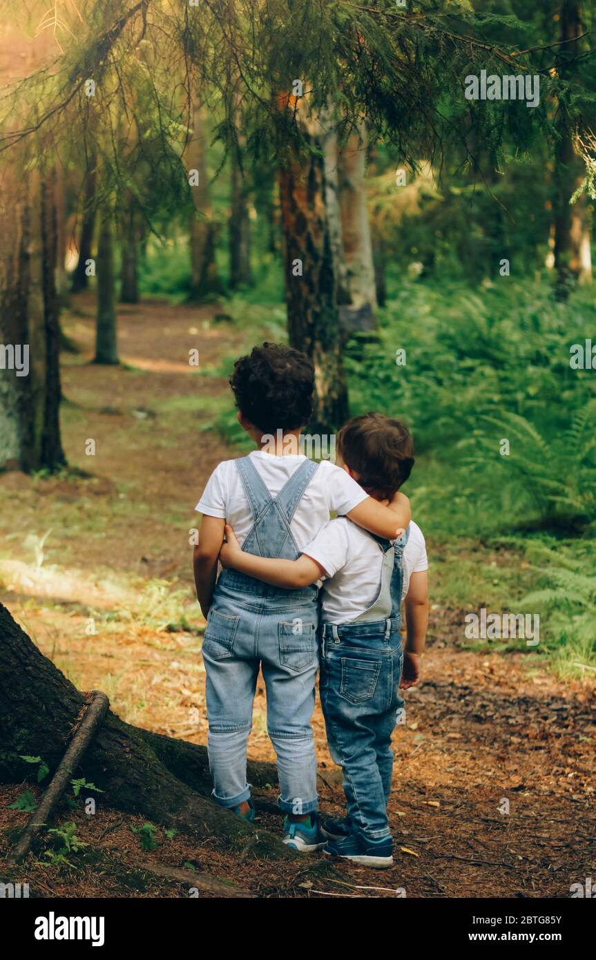 Due ragazzini, amici si abbracciano in estate soleggiato giorno nella foresta. Amore fratello. Vista posteriore. In attesa di futuro. Foto Stock
