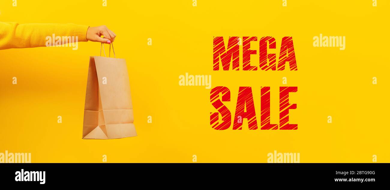 borsa di carta in mano su sfondo giallo, iscrizione mega vendita, immagine panoramica Foto Stock