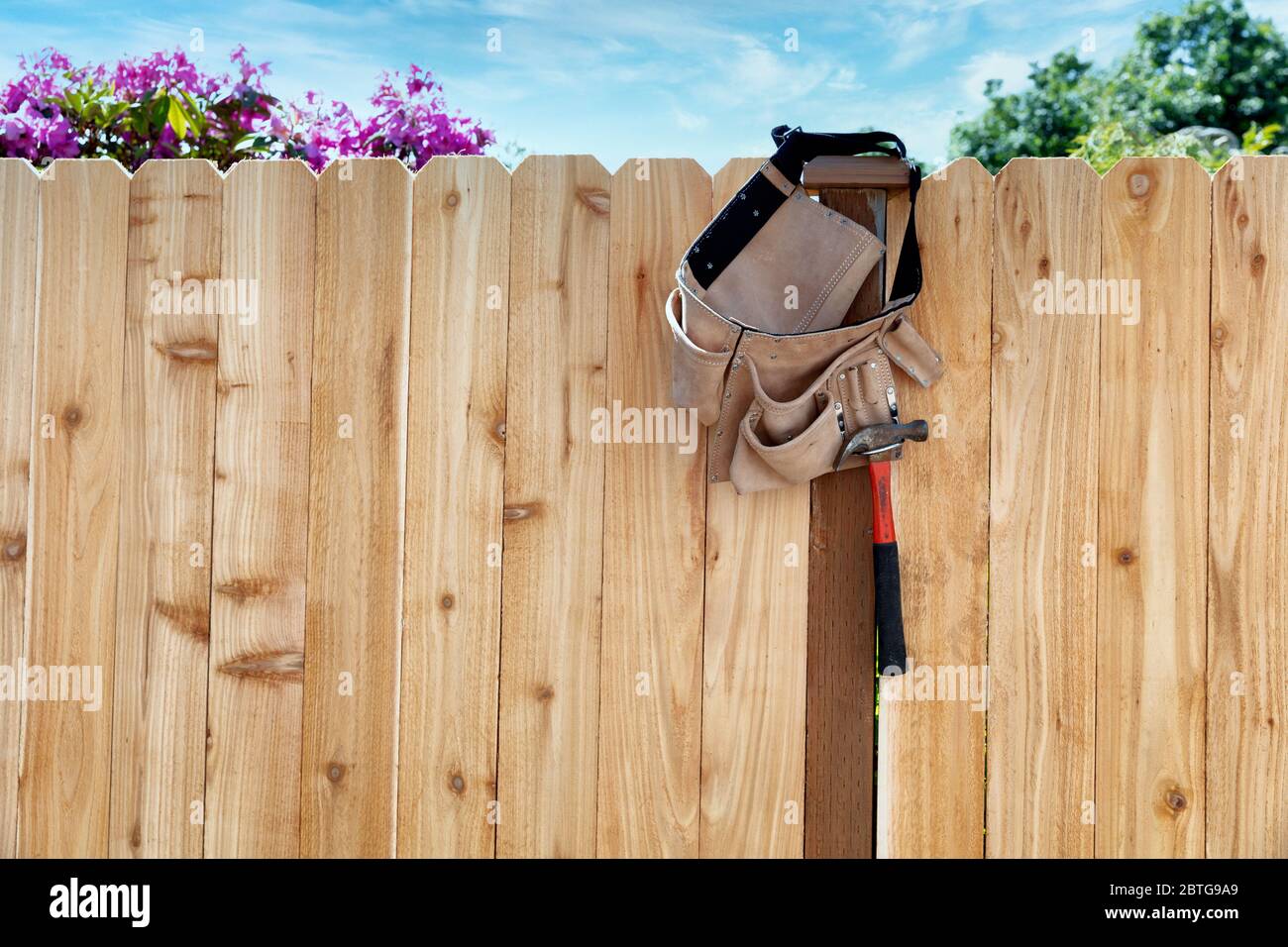 Nuova recinzione in legno con cintura portautensili e tasca appesa al palo Foto Stock