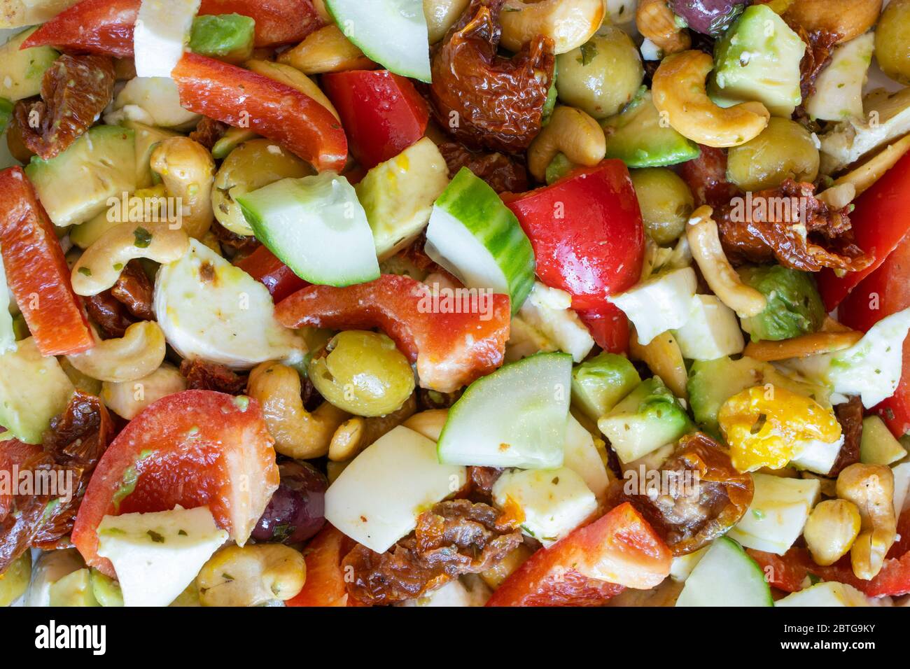 Una salutare insalata vegetariana in stile mediterraneo fatta in casa con cetrioli, peperoni rossi, mozzarella, noci di anacardi, pomodori secchi, olive e uova Foto Stock