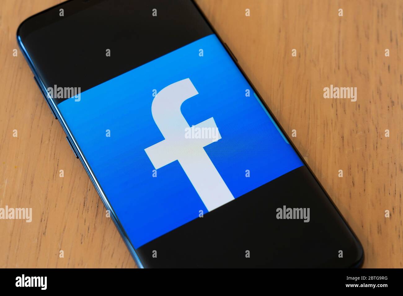 Un grande logo per l'applicazione social media Facebook su uno schermo smartphone su un tavolo di legno su un Samsung Galaxy S8 Foto Stock