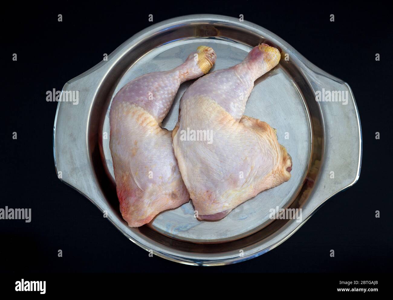 Cosce di pollo grezze in lamiera su fondo nero isolato Foto Stock