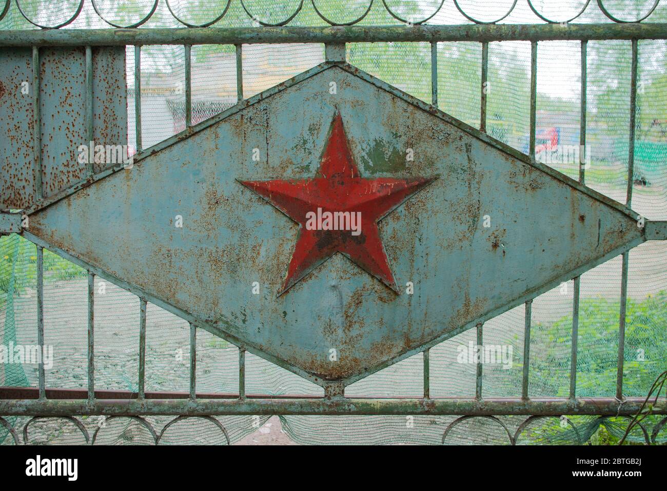 Stella militare sovietica a cinque punte sul cancello verde. Zona limitata abbandonata Foto Stock