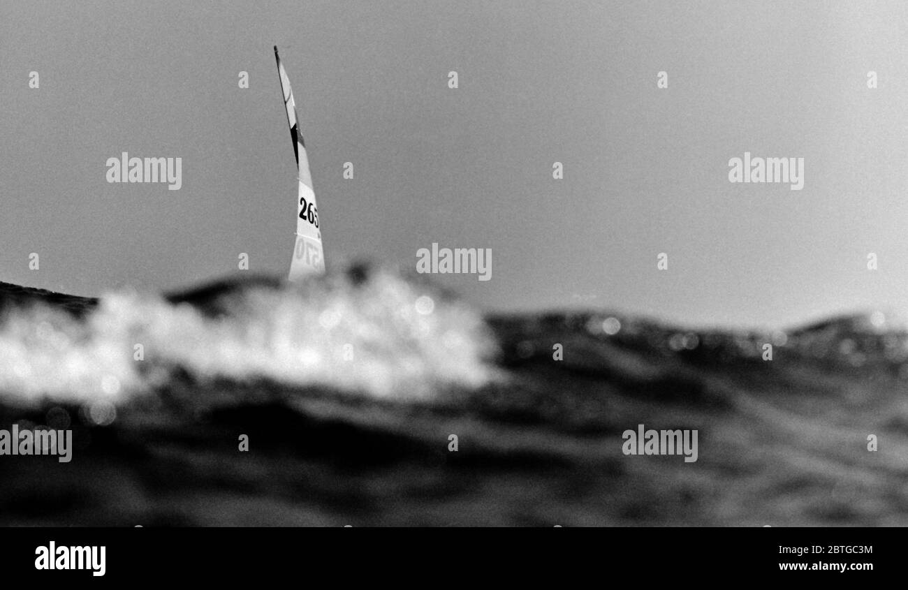 AJAXNETPHOTO. 1977. BAIA DI LAS SALINAS, LANZAROTE, SPAGNA. - UN CONCORRENTE CHE CORRE IN UNA BREZZA FRANGENTE E IN ACQUE AGITATE NEI CAMPIONATI MONDIALI HOBIE CAT 14 SCOMPARE DIETRO L'ONDA DELL'ATLANTICO. PHOTO:JONATHAN EASTLAND/AJAX REF:7726091 80 Foto Stock