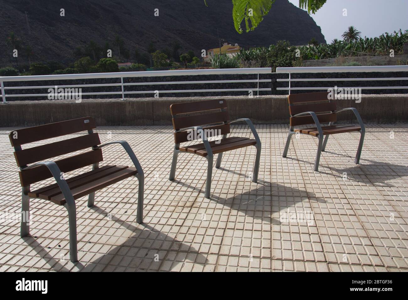 Posti a sedere individuali in legno in un parco pubblico con separazione per mantenere le distanze sociali Foto Stock