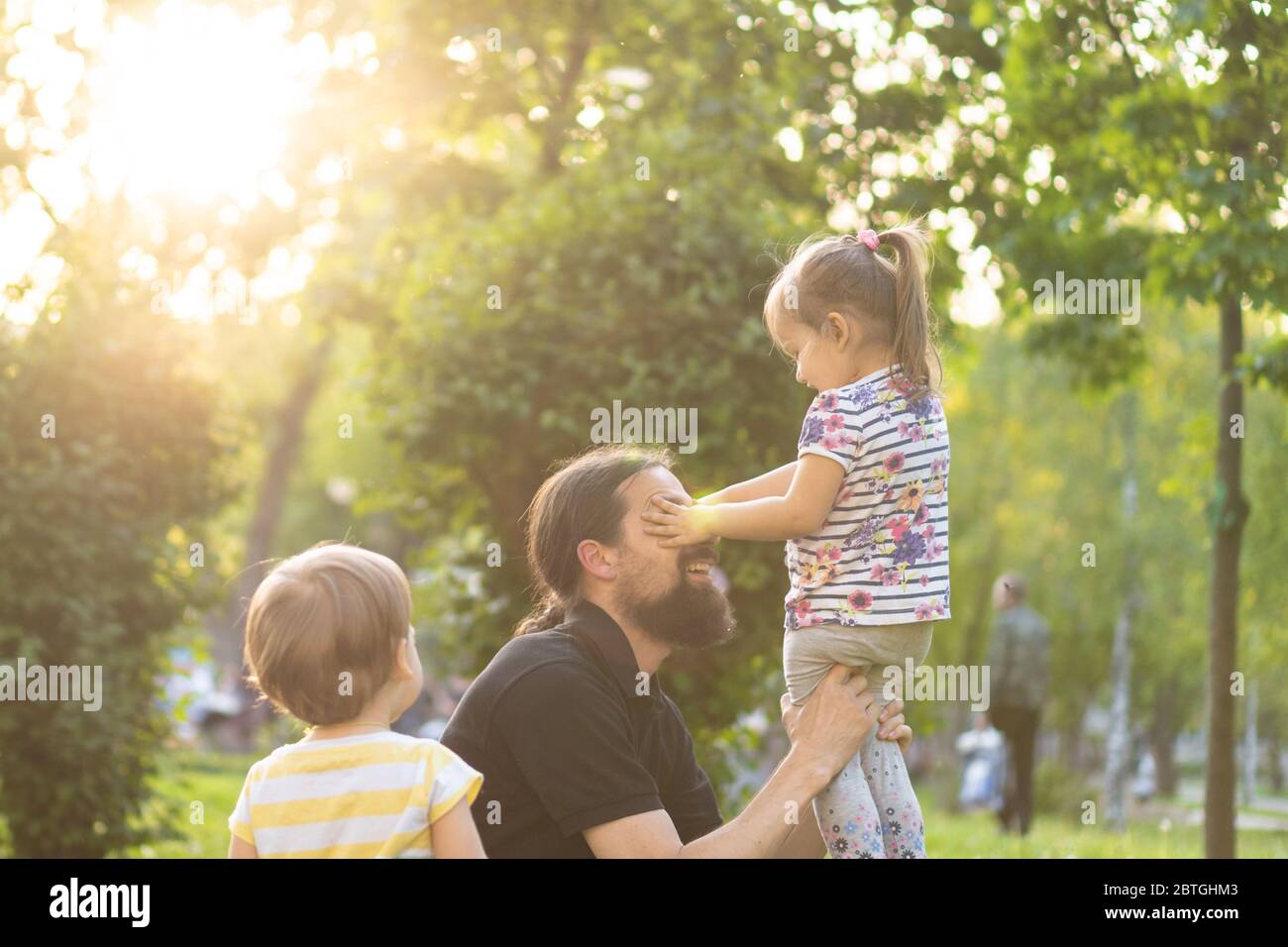Paternità, paternità, infanzia, cura, estate e tempo libero - giovane papà con barba e capelli lunghi in t-shirt nera che tiene il suo piccolo Foto Stock
