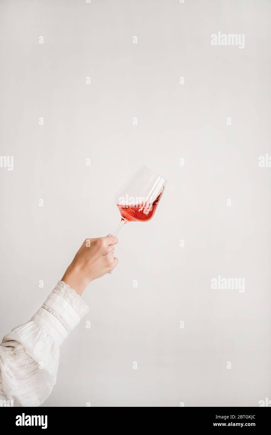 Bicchiere di vino rosa girante e tenuta a mano delle donne durante la degustazione Foto Stock