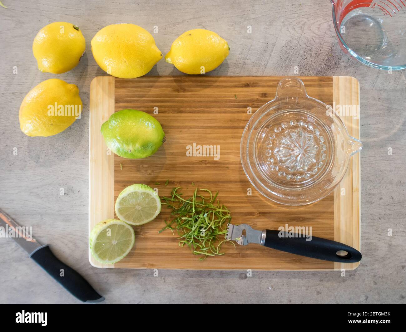 Utilizzando una centrifuga a mano in vetro e uno zester, estrarre il succo e macinare i limoni e i lime per una ricetta Foto Stock