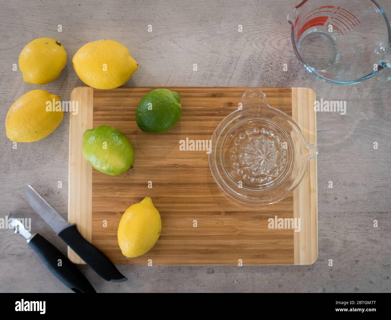 Utilizzando una centrifuga a mano in vetro e uno zester, estrarre il succo e macinare i limoni e i lime per una ricetta Foto Stock