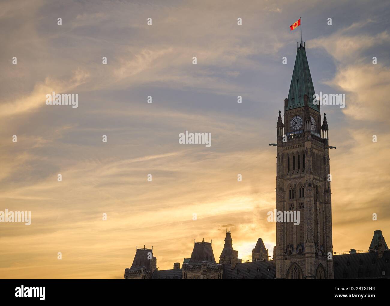 Il sole tramonta dietro il blocco centrale degli edifici del parlamento canadese a Ottawa contro un cielo vibrante della sera. Foto Stock