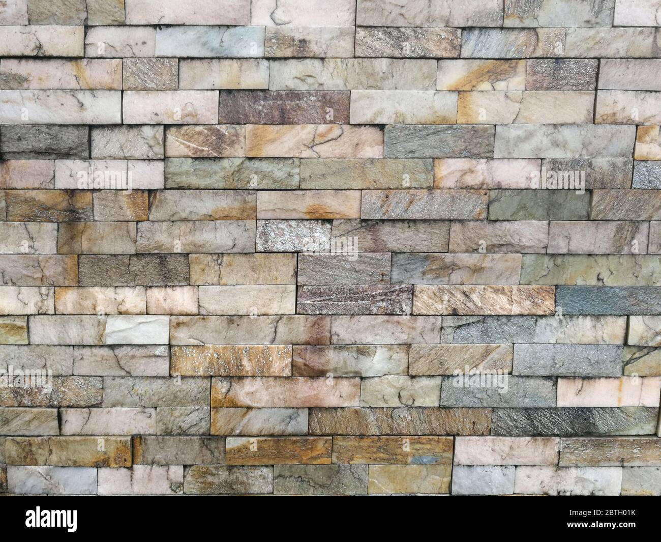 Mattoni colorati, pietre di pavimentazione, impilati come un muro, come sfondo Foto Stock