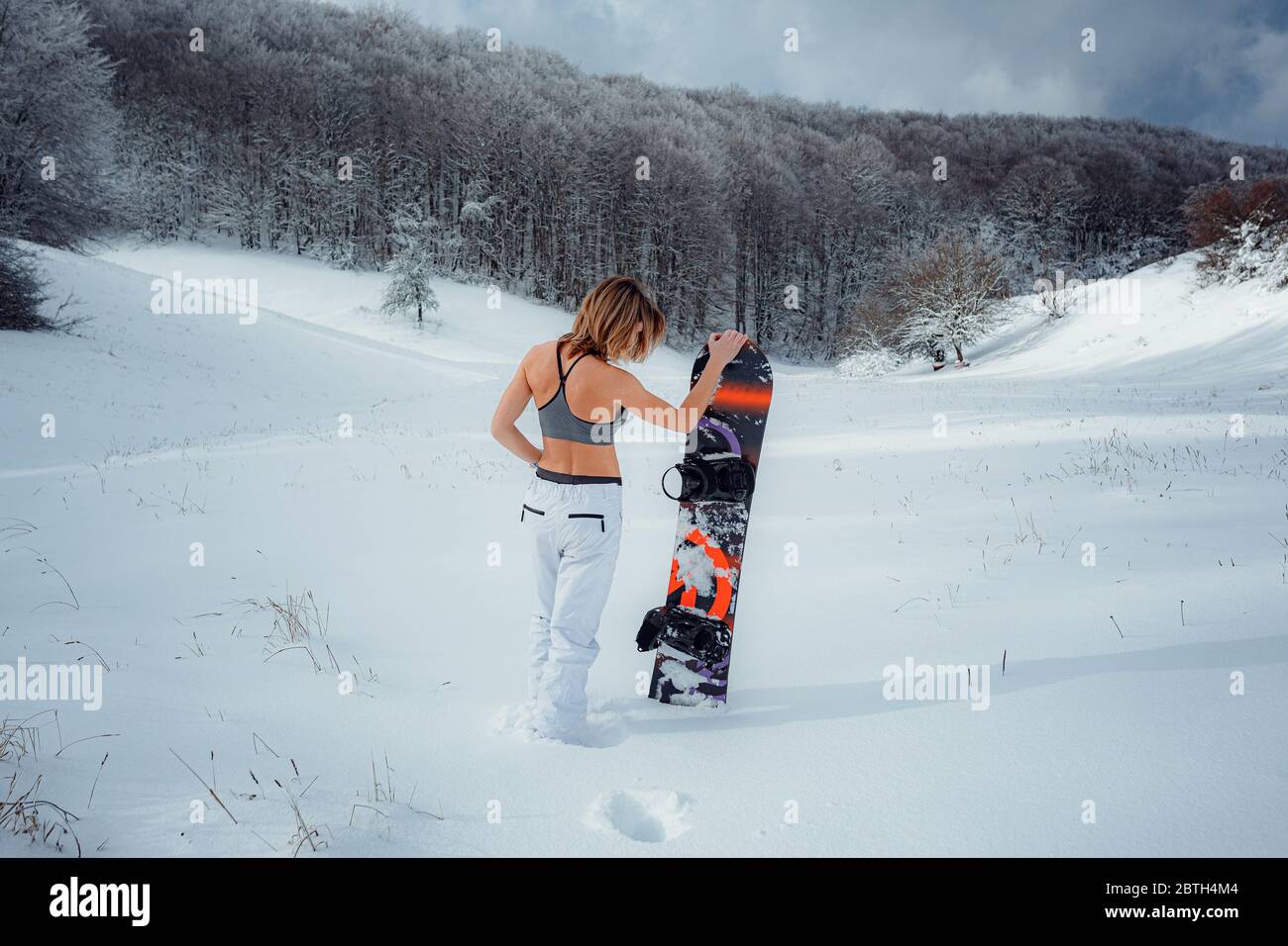 Snowboarder femminile tiene snowboard e andare a snowboard. Attività di  sport invernali, foresta neve all'aperto stile di vita. Ragazza che indossa  un tetto corto e sci w Foto stock - Alamy