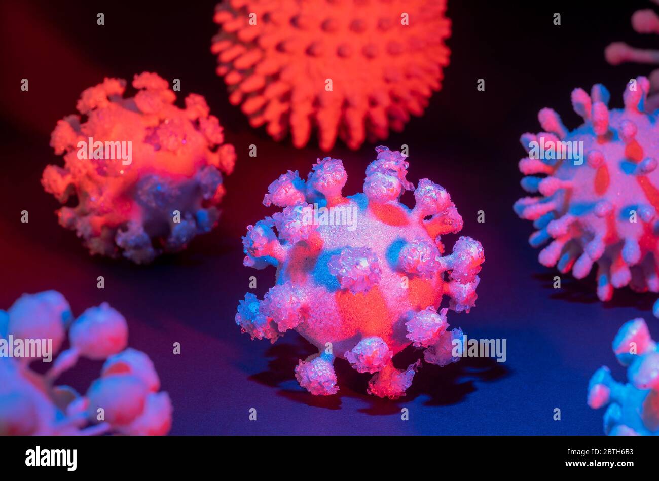 immagine di alcuni colorati virus simbolici illuminati sul retro scuro Foto Stock