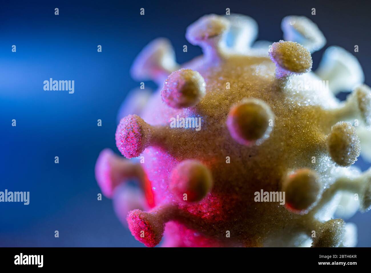 dettaglio di un colorato virus simbolico illuminato nel buio posteriore Foto Stock