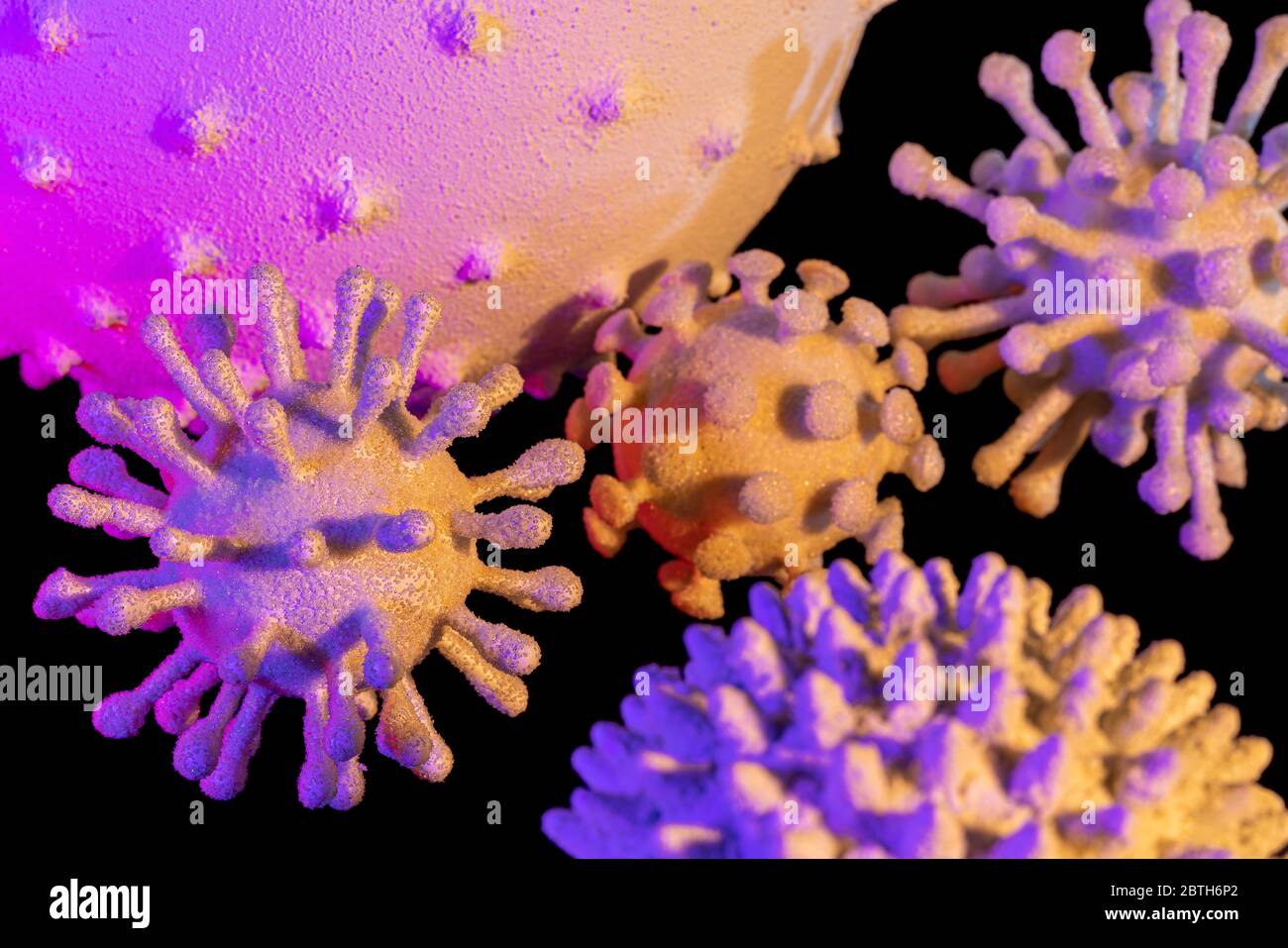 immagine di alcuni colorati virus simbolici illuminati in nero sul retro Foto Stock