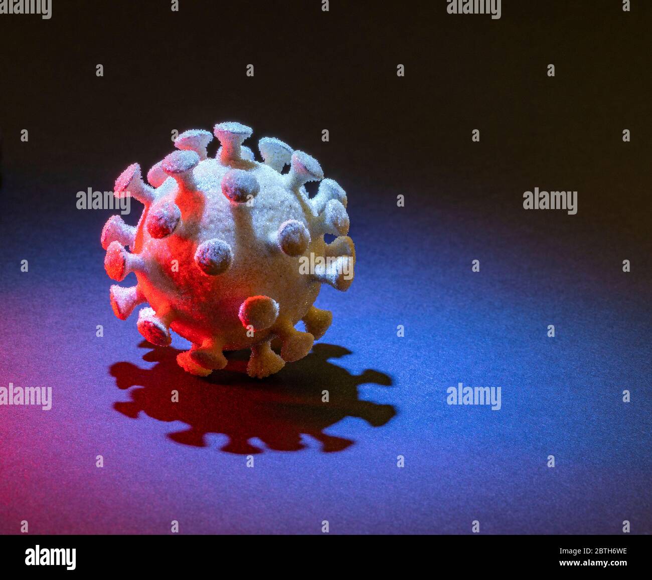 un virus simbolico illuminato colorato nel dorso scuro Foto Stock