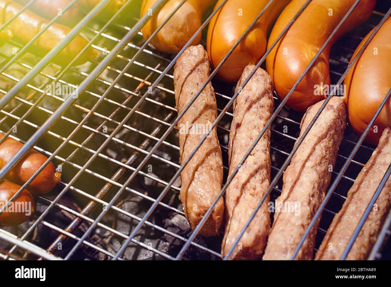 salsicce di carne, giwapchichi e salsicce si trovano sul ferro griglia effetto sole flare Foto Stock