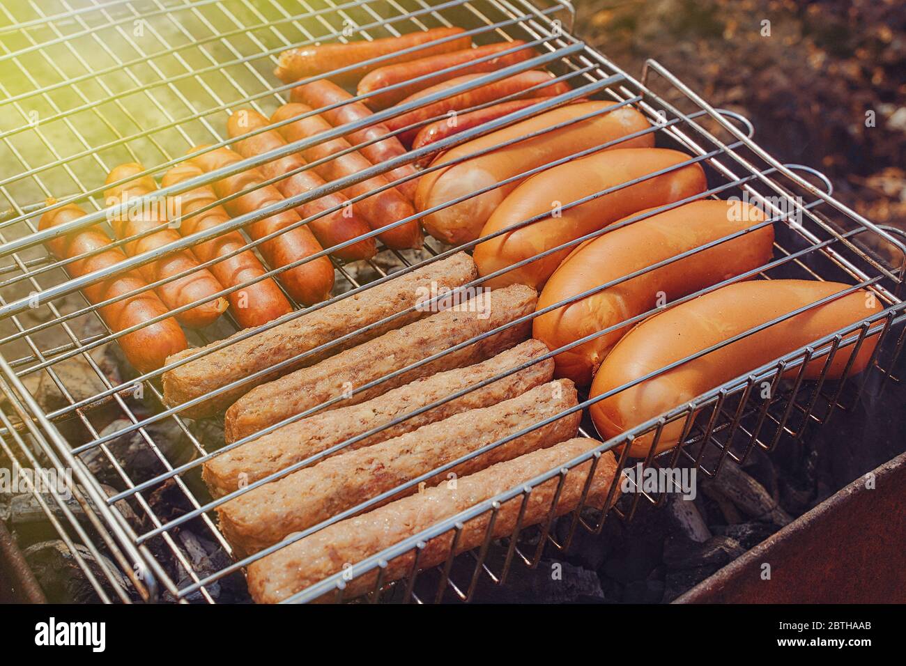 salsicce di carne, giwapchichi e salsicce si trovano sulla griglia di ferro sole flare Foto Stock