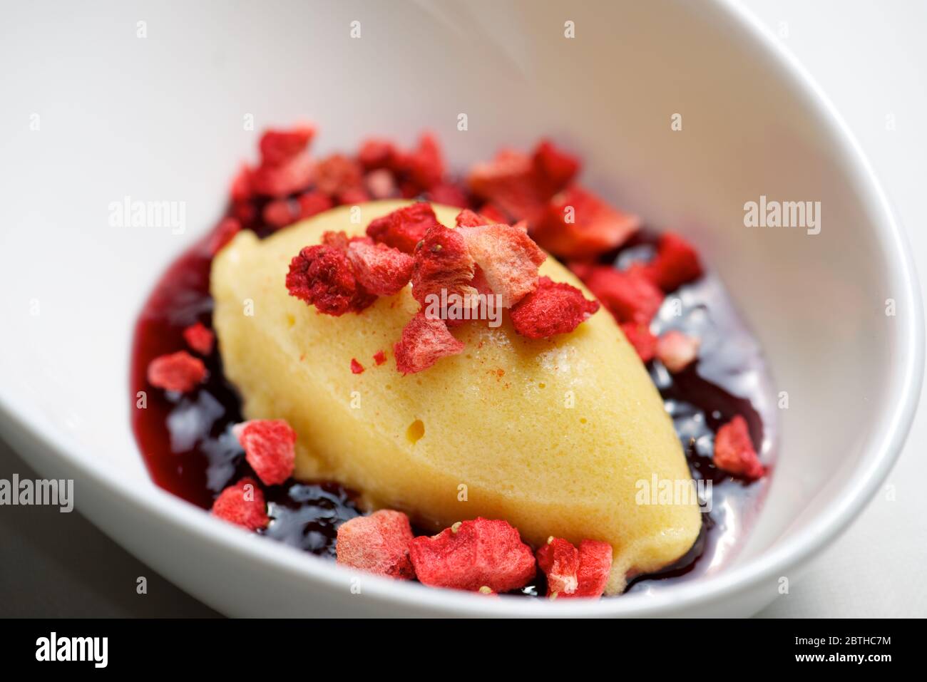 Gelato alla pesca con fragola su una ciotola bianca. Foto Stock