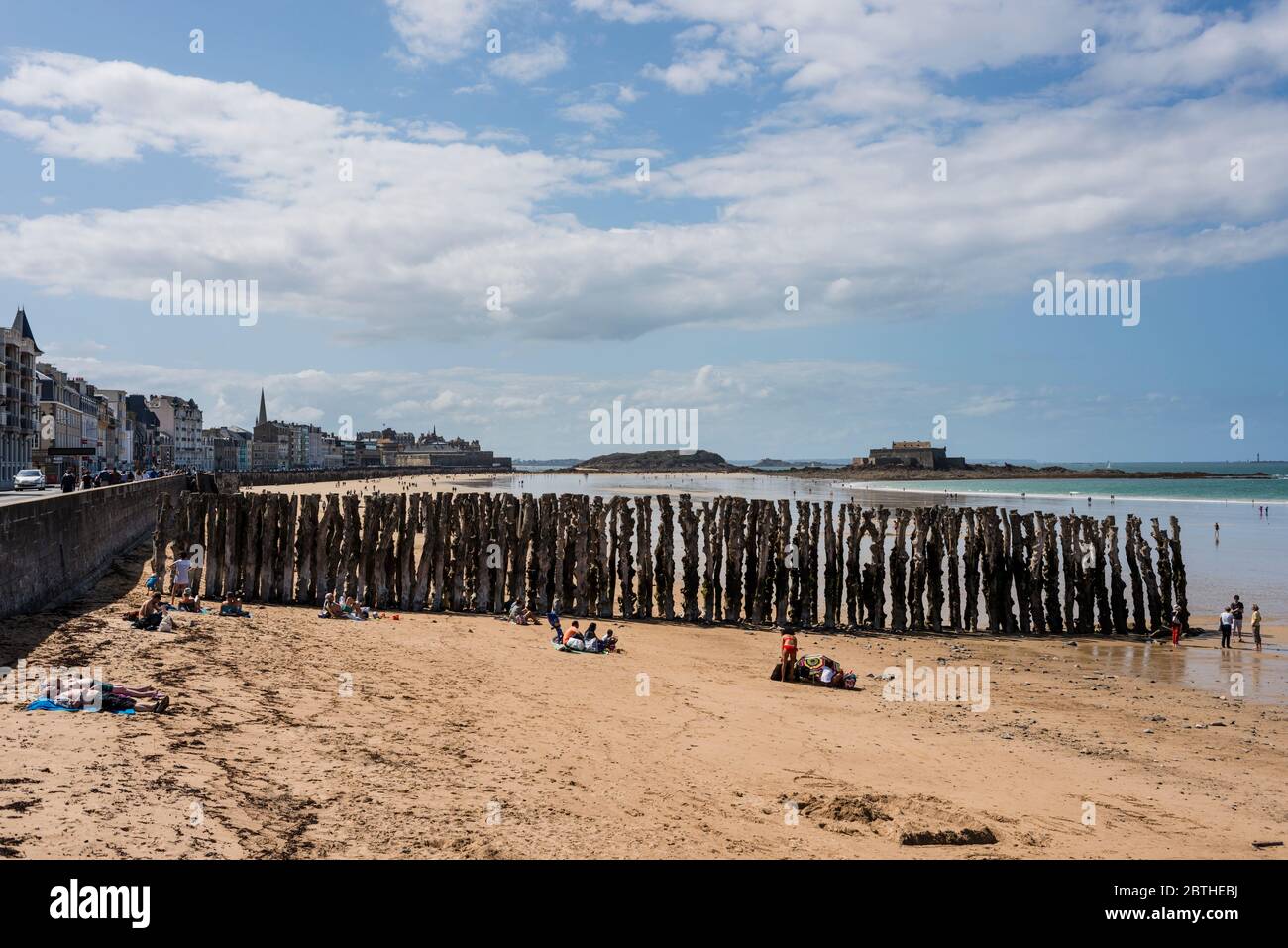 Per coloro che godono di sole sulla spiaggia sabbiosa di Saint Malo, Le Grand Bé e Fort National in background, Bretagna Francia Foto Stock