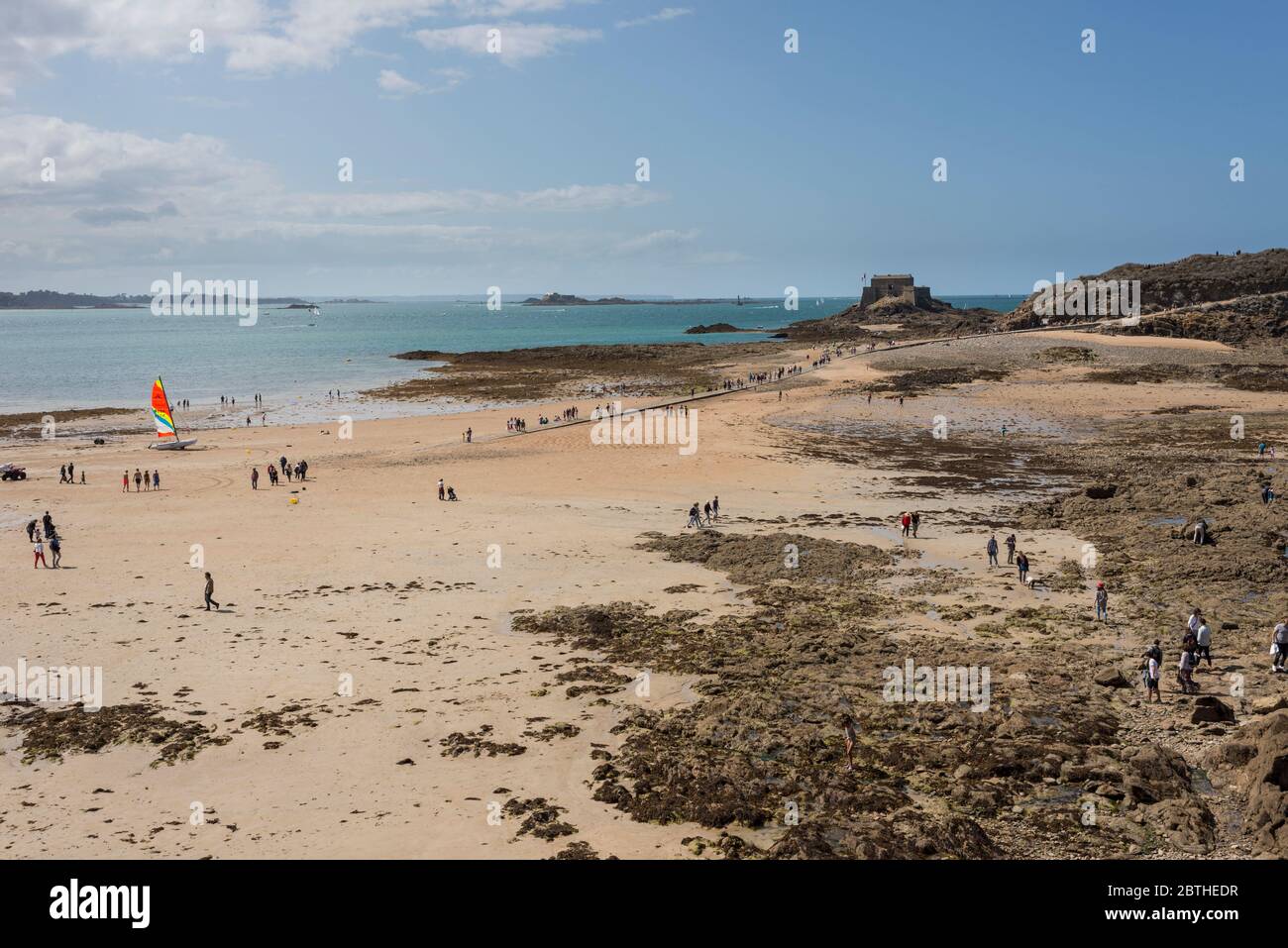 La gente sulla spiaggia sabbiosa e la vista del mare con il Fort National in background, Bretagna Francia Foto Stock