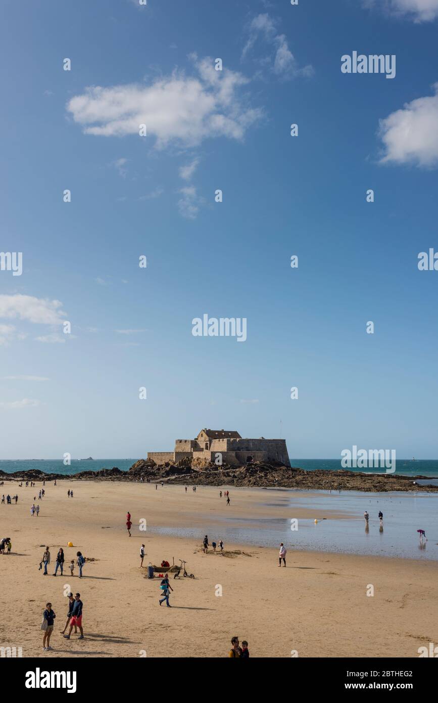 La gente sulla spiaggia sabbiosa e la vista del mare con il Fort National in background, Bretagna Francia Foto Stock