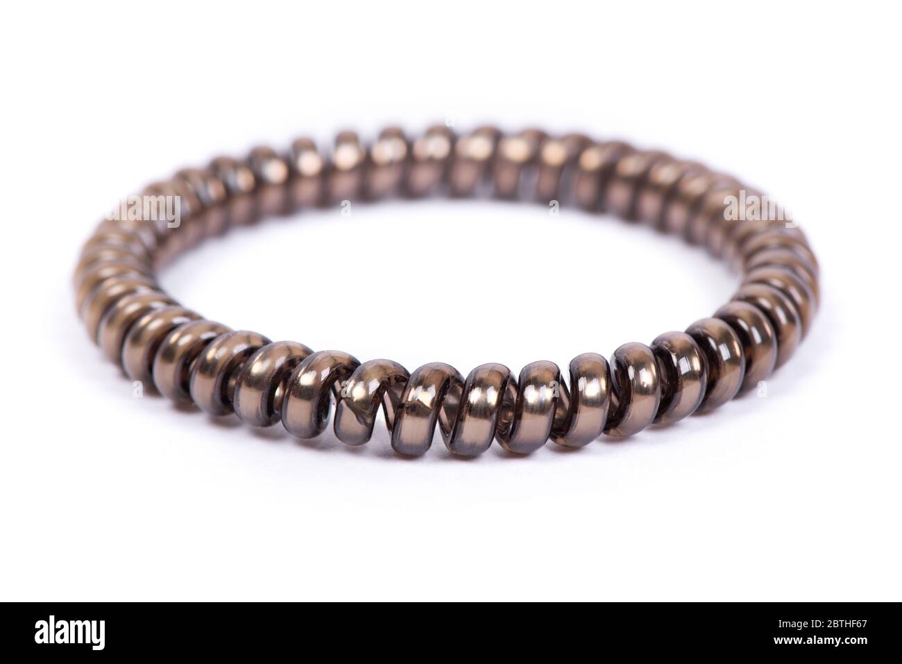 Una spirale elastica marrone per capelli isolati su sfondo bianco. Articolo in plastica flessibile per capelli femminili o braccialetti. Foto Stock
