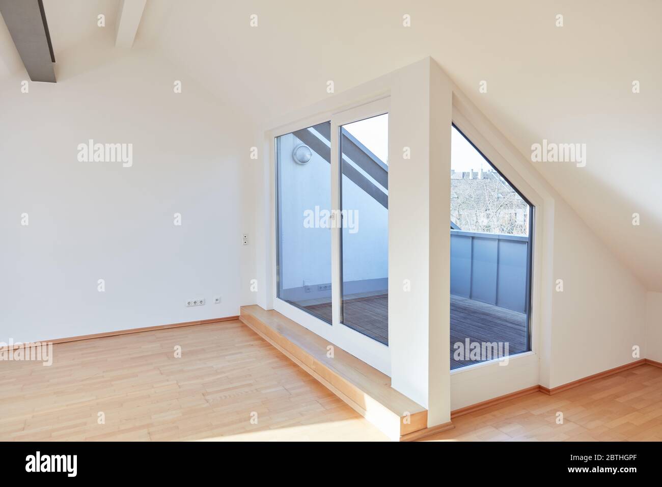 Camera vuota in un moderno e luminoso appartamento mansardato con terrazza o balcone sul tetto Foto Stock