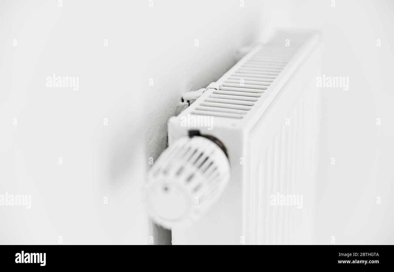 Riscaldamento con radiatore a pannello bianco e termostato sulla parete di un appartamento Foto Stock