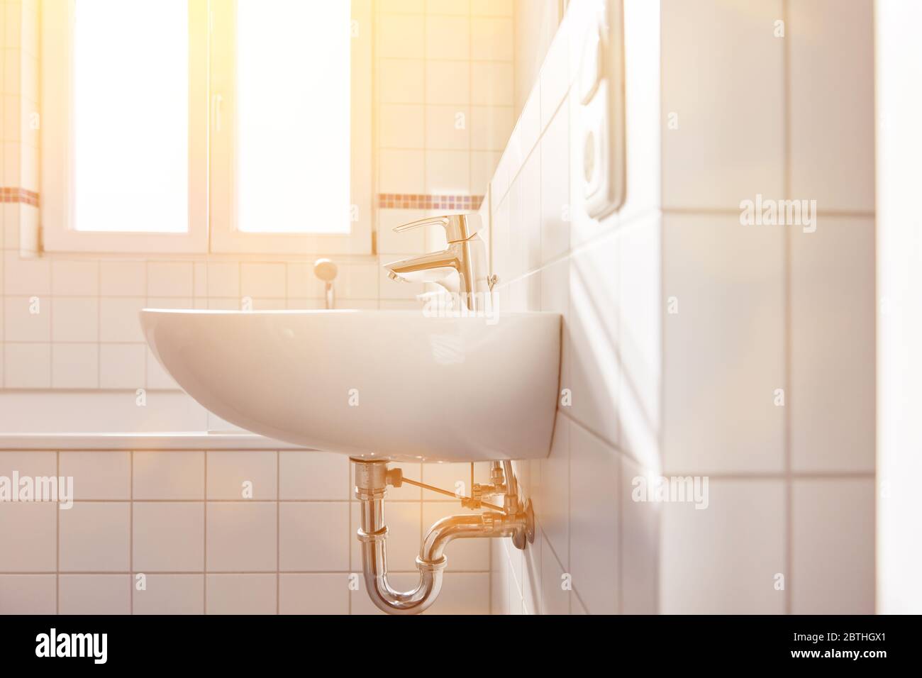 Lavabo in bagno bianco luminoso con finestra per luce naturale e sole Foto Stock