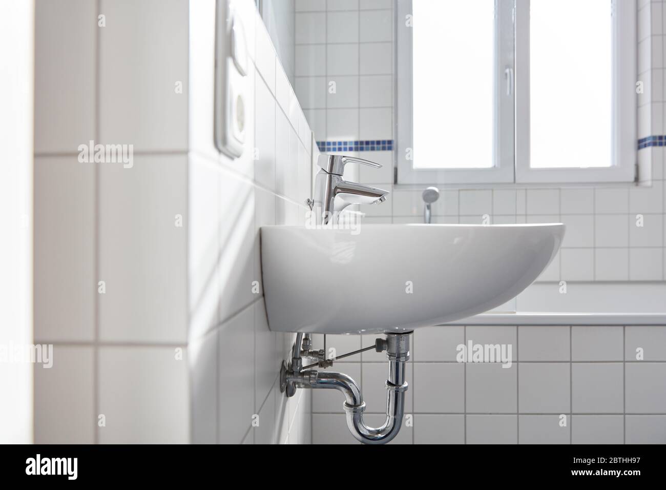 Lavabo con rubinetto in bagno bianco luminoso con finestra per luce naturale Foto Stock