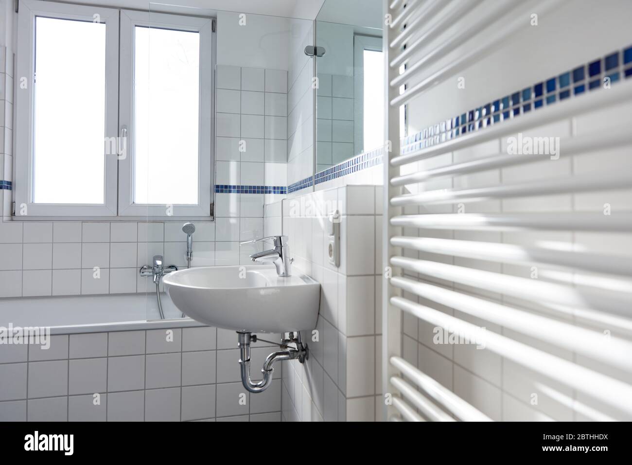 Lavabo in ceramica bianca in bagno luminoso con radiatore e finestra Foto Stock