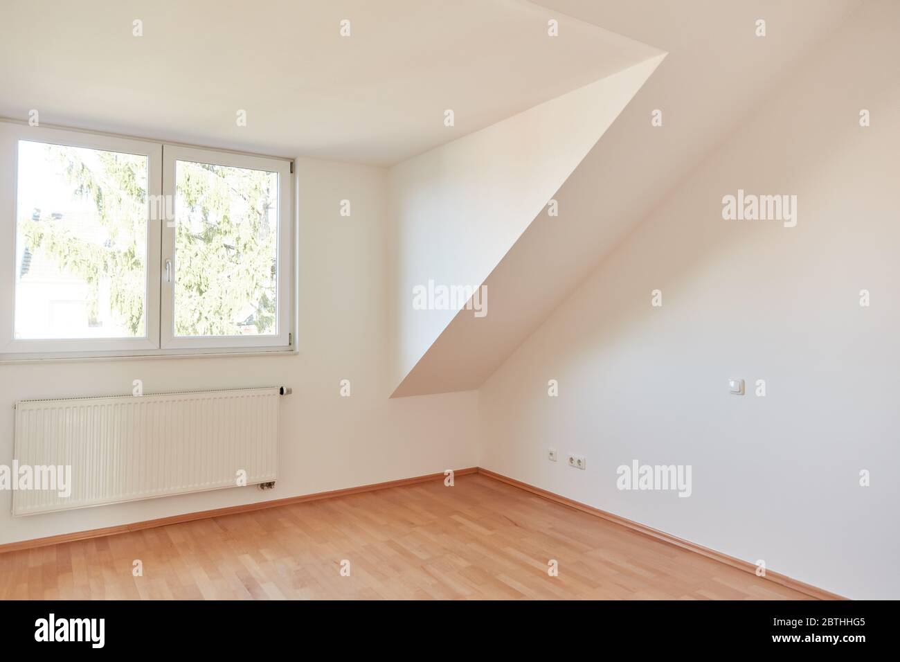 Camera vuota e luminosa, situata all'ultimo piano, con finestra e riscaldamento Foto Stock