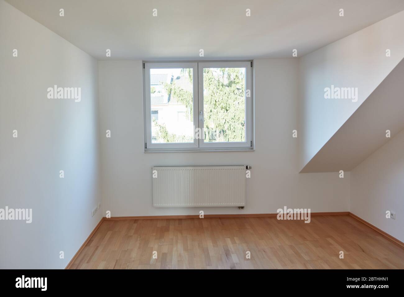 Camera interna vuota nella mansarda con parquet in legno e pareti bianche Foto Stock