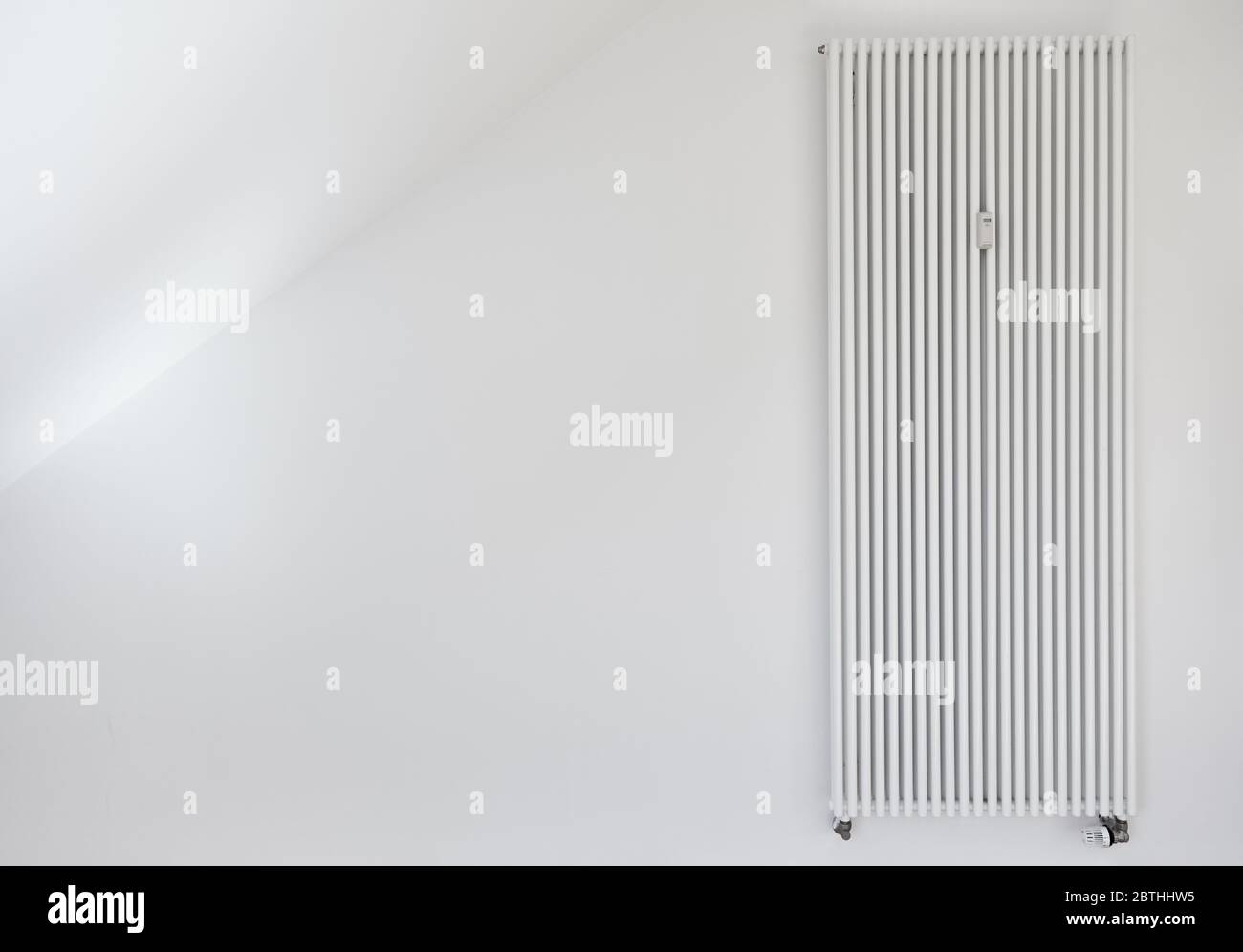 Stufa bianca con lungo radiatore tubolare sulla parete di un appartamento Foto Stock