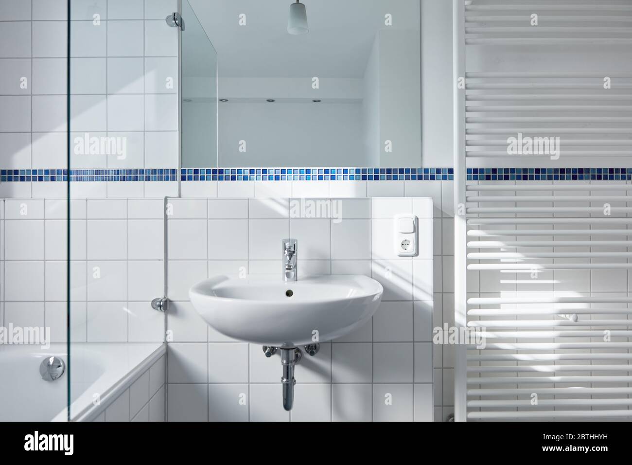Bagno moderno e luminoso con lavello e vasca e radiatore tubolare Foto Stock