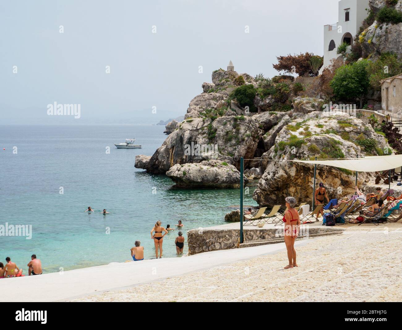 Sicilia, 2019 giugno, spiaggia privata rocciosa in sicilia con turisti e locali che fanno bagni e rilassarsi Foto Stock