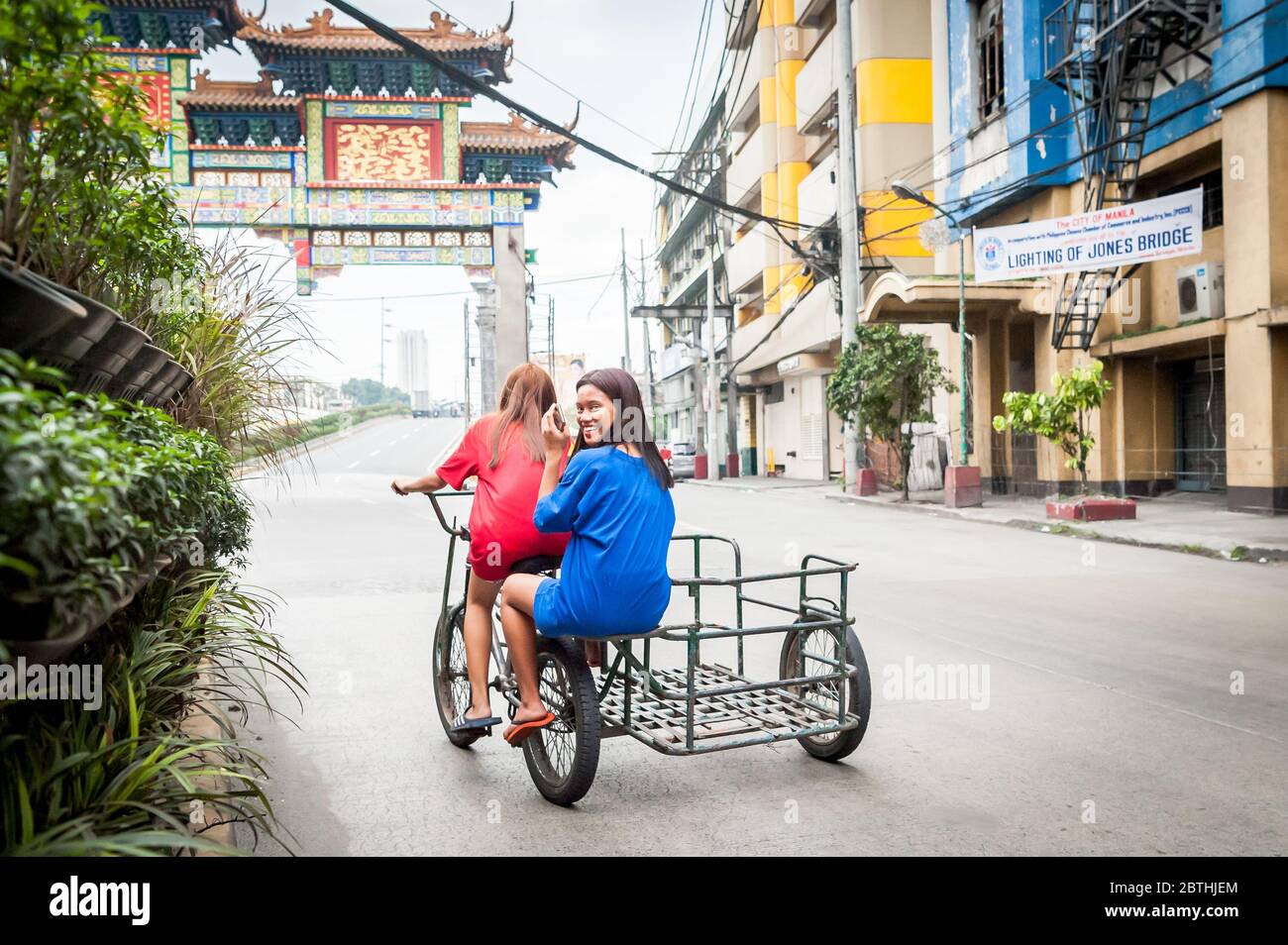 Due filippini locali attraversano l'incrocio trafficato all'Arco dell'amicizia Cinese Filippino nel quartiere di Binondo Chinatown a Manila, Filippine. Foto Stock