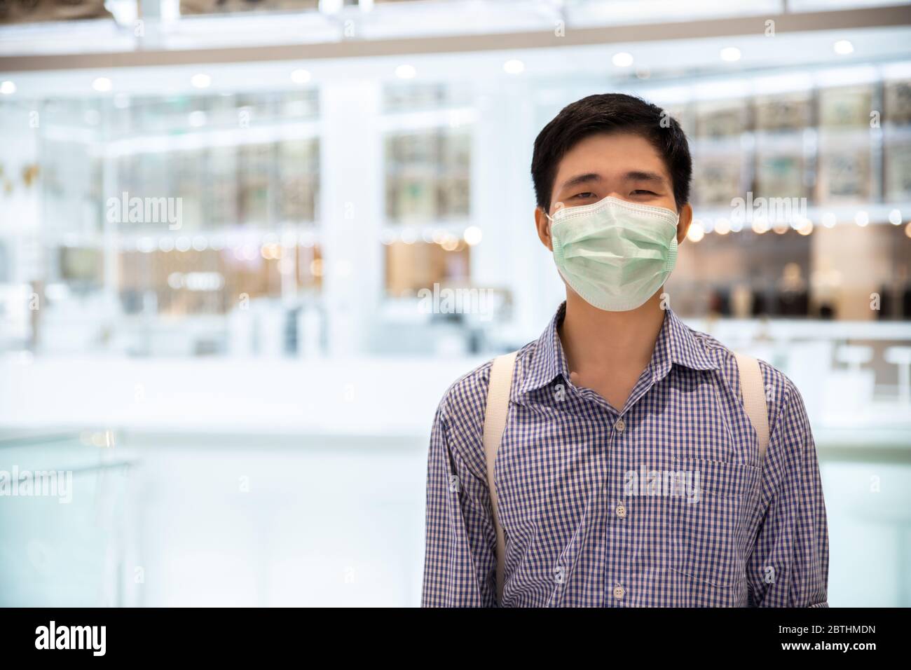 Uomo asiatico sorridente dietro maschera medica protettiva in nuovo concetto di stile di vita normale. Foto Stock