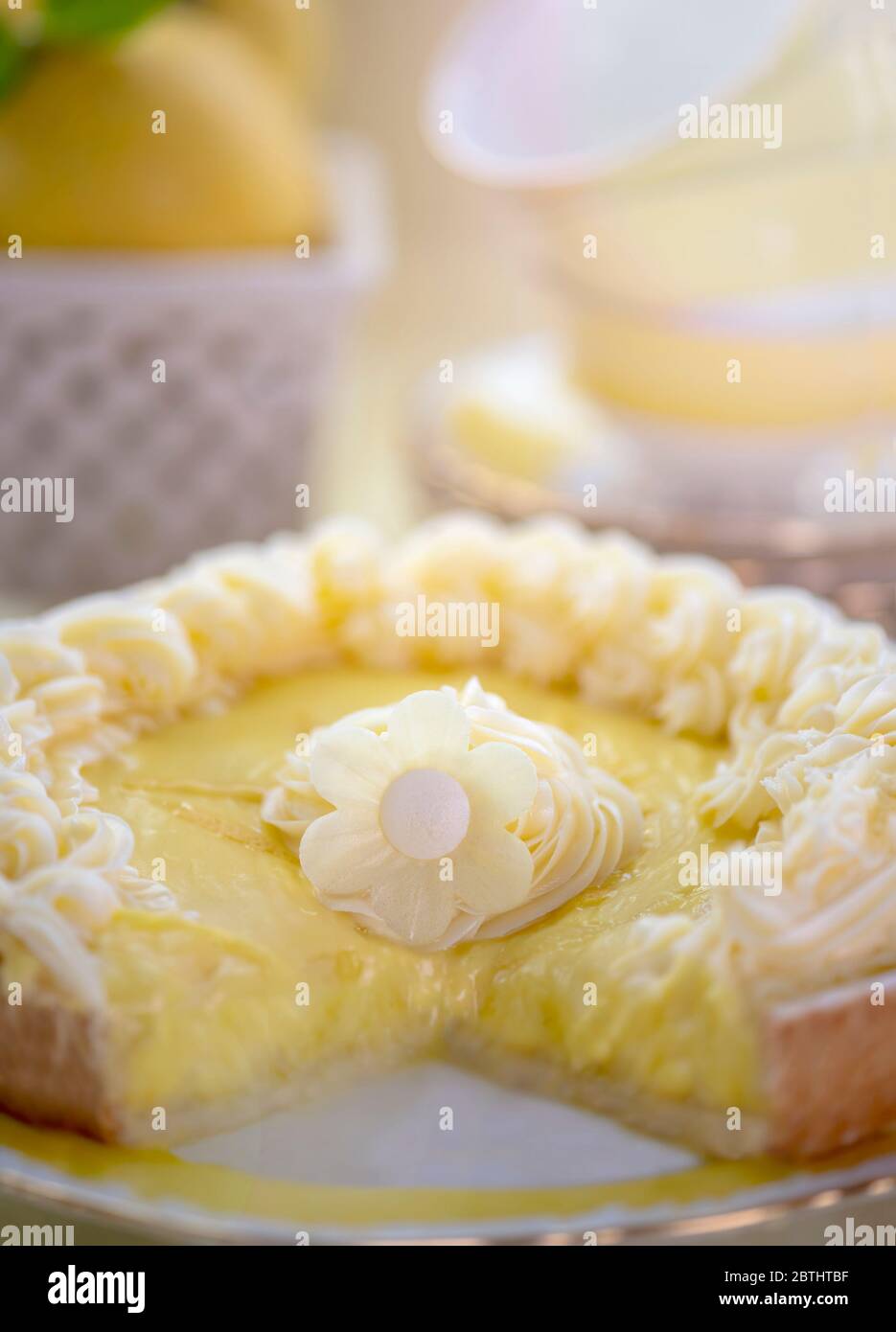 Primo piano di deliziosa crostata al limone con succosa mousse texture e crema di burro in cima con fiore decorativo al centro messo vicino al set da tè. Shot per copia spa Foto Stock
