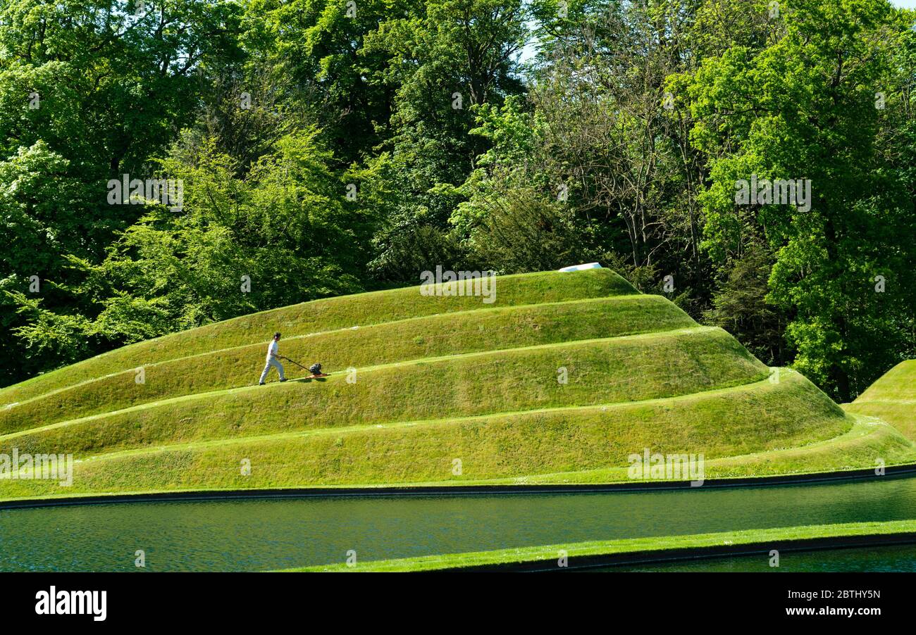 Wilkieston, Scozia, Regno Unito. 26 maggio 2020. Thomas Unterdorfer, custode del paesaggio a Giove Artland, tagliando l'erba sulle sculture in terraferma celle di vita di Charles Jencks. Jupiter Artland spera di avere un'apertura limitata nel prossimo futuro, quando le regole di blocco di Covid-19 sono rilassati. Iain Masterton/Alamy Live News Foto Stock