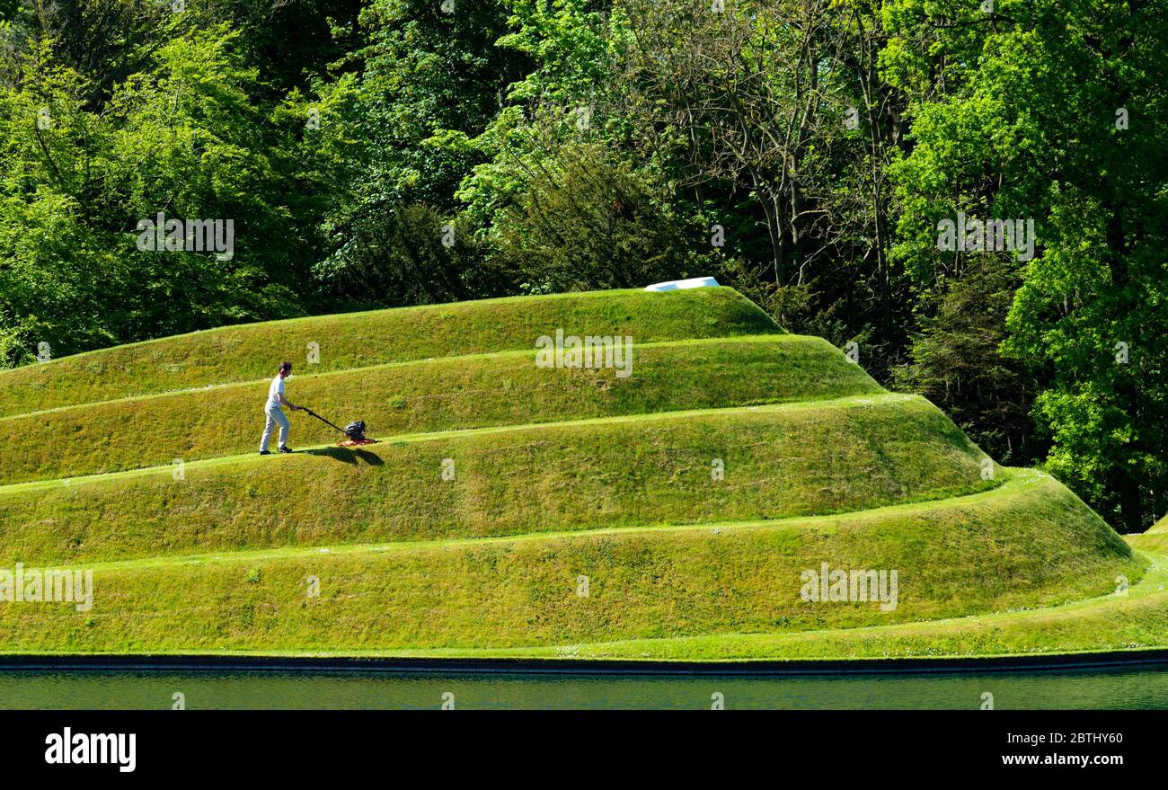 Wilkieston, Scozia, Regno Unito. 26 maggio 2020. Thomas Unterdorfer, custode del paesaggio a Giove Artland, tagliando l'erba sulle sculture in terraferma celle di vita di Charles Jencks. Jupiter Artland spera di avere un'apertura limitata nel prossimo futuro, quando le regole di blocco di Covid-19 sono rilassati. Iain Masterton/Alamy Live News Foto Stock