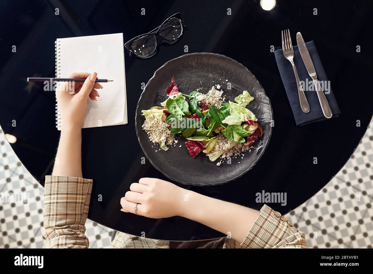 Concetto di pianificazione alimentare e dietetica sana. Donna che usa il notebook e mangia insalata fresca, vista dall'alto Foto Stock