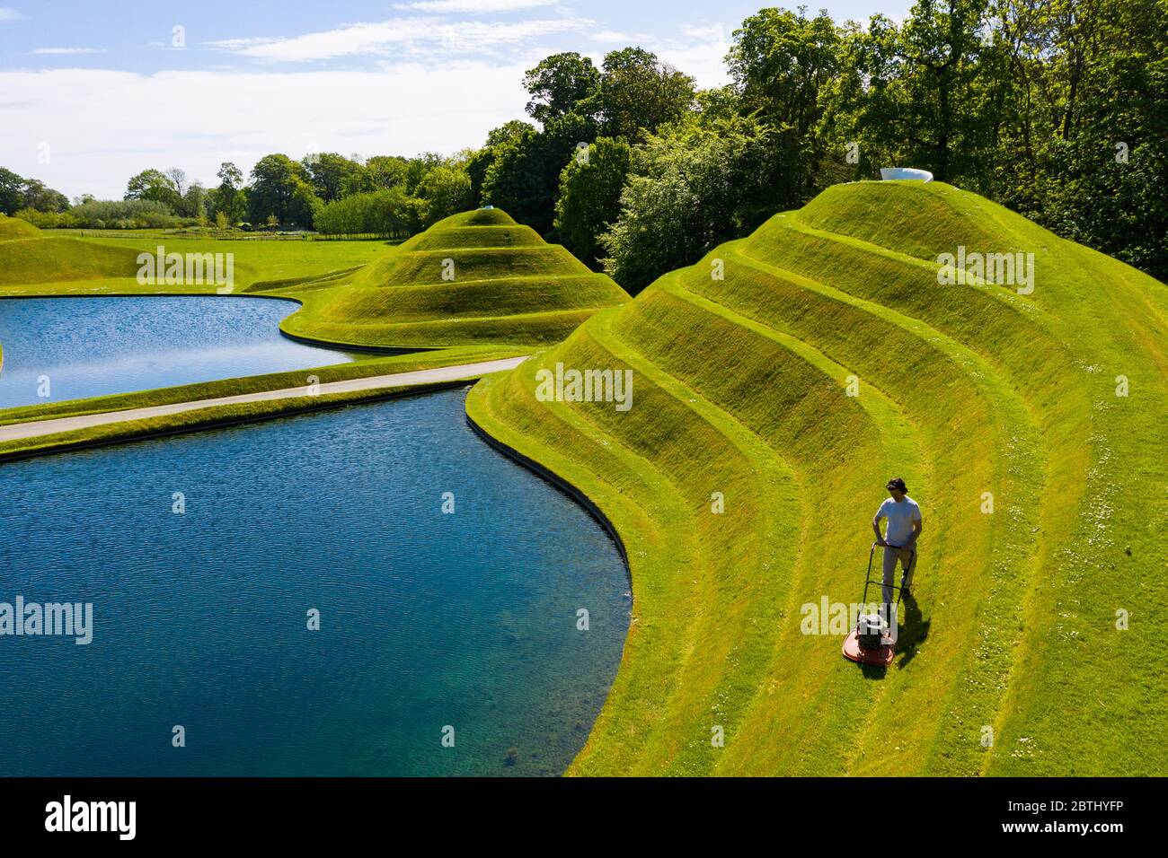 Wilkieston, Scozia, Regno Unito. 26 maggio 2020. Thomas Unterdorfer, custode del paesaggio a Giove Artland, tagliando l'erba sulle sculture in terraferma celle di vita di Charles Jencks. Jupiter Artland spera di avere un'apertura limitata nel prossimo futuro, quando le regole di blocco di Covid-19 sono rilassati. Iain Masterton/Alamy Live News Foto Stock