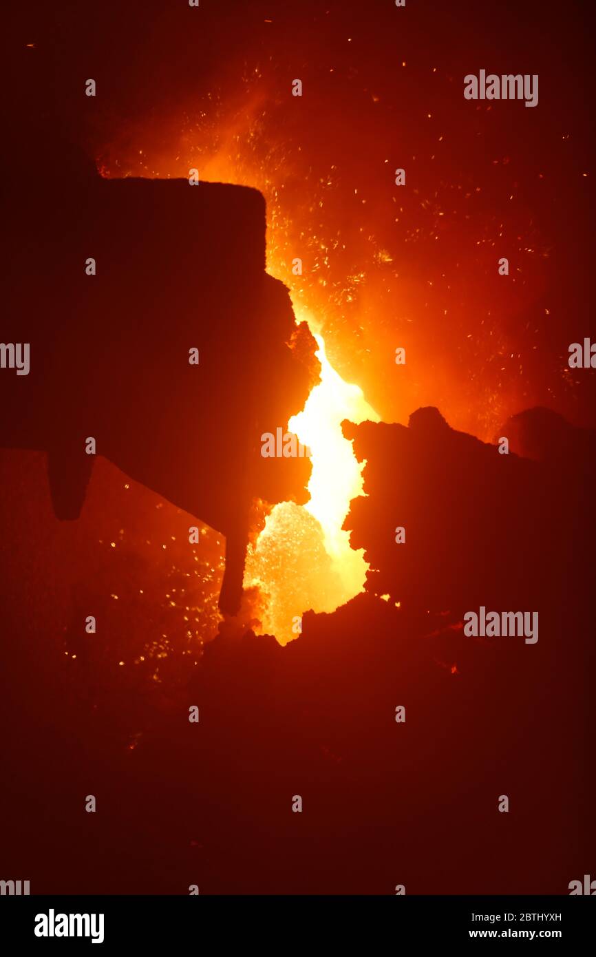 Metallo fuso caldo proveniente da altoforno con bagliore arancione e scintille Foto Stock