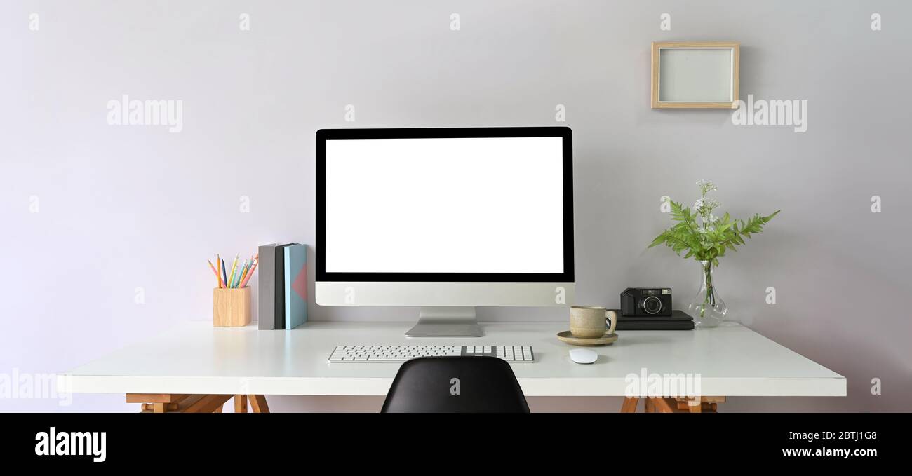 Computer Workspace schermo vuoto e materiale creativo per ufficio sulla scrivania con cornice fotografica. Foto Stock