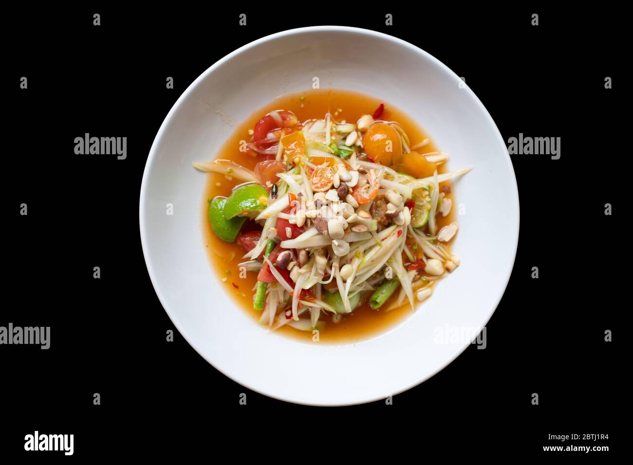 insalata di papaya verde in ciotola bianca isolata su sfondo nero. Cibo tailandese delizioso e popolare Foto Stock