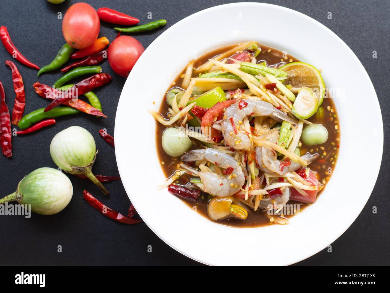 Insalata di papaya con gamberi in bianco su sfondo nero. Cibo tailandese delizioso e popolare Foto Stock