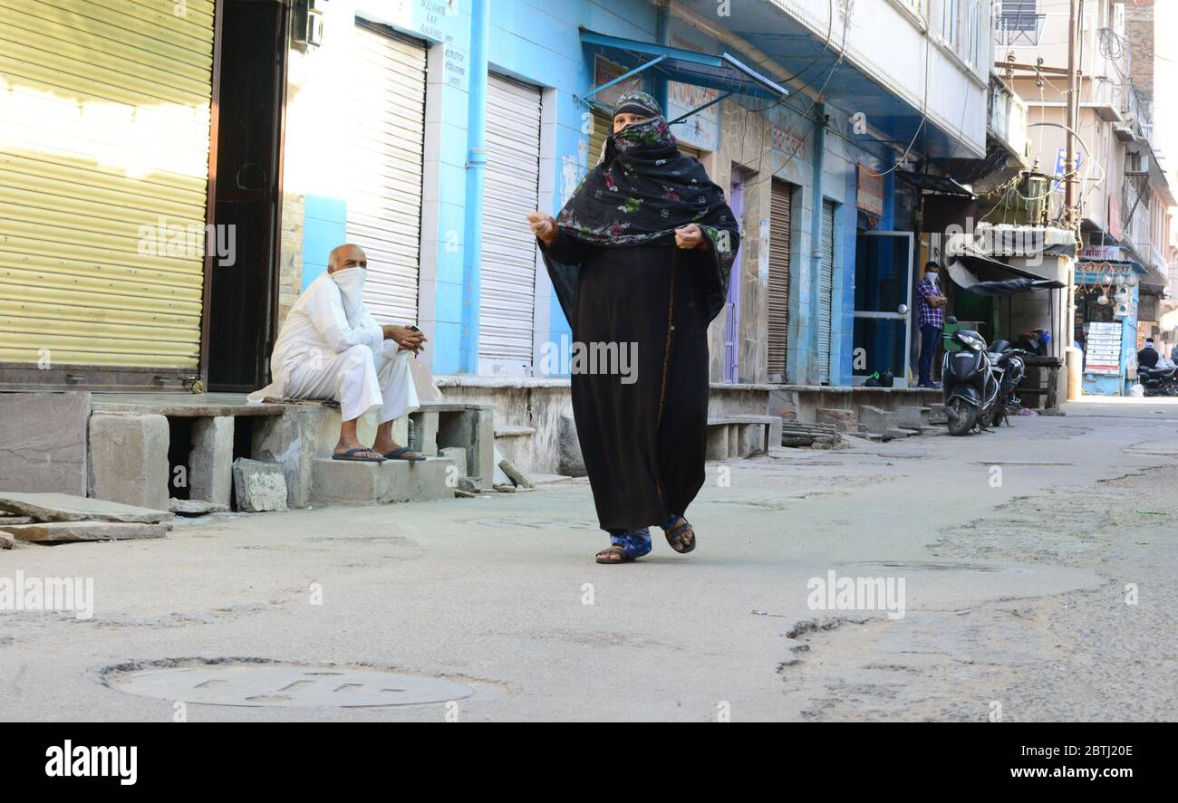 Una donna musulmana cammina di fronte a negozi chiusi davanti a Eid al-Fitr durante il mese santo di Ramzan a Beawar, Rajasthan. Foto Stock