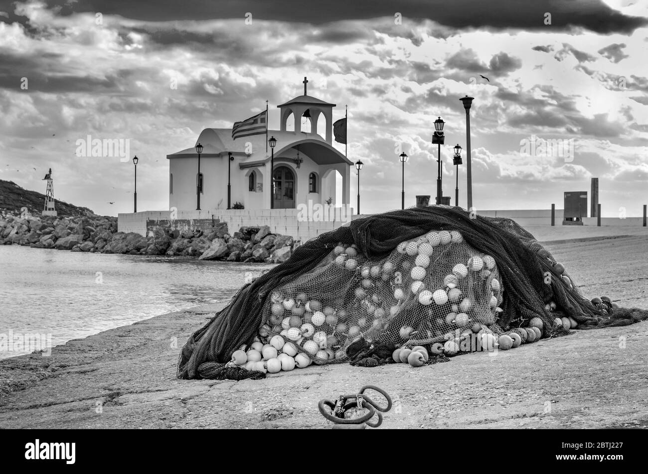 Una piccola cappella greca sul mare e una piccola baia sotto un cielo drammatico su un'isola greca Foto Stock